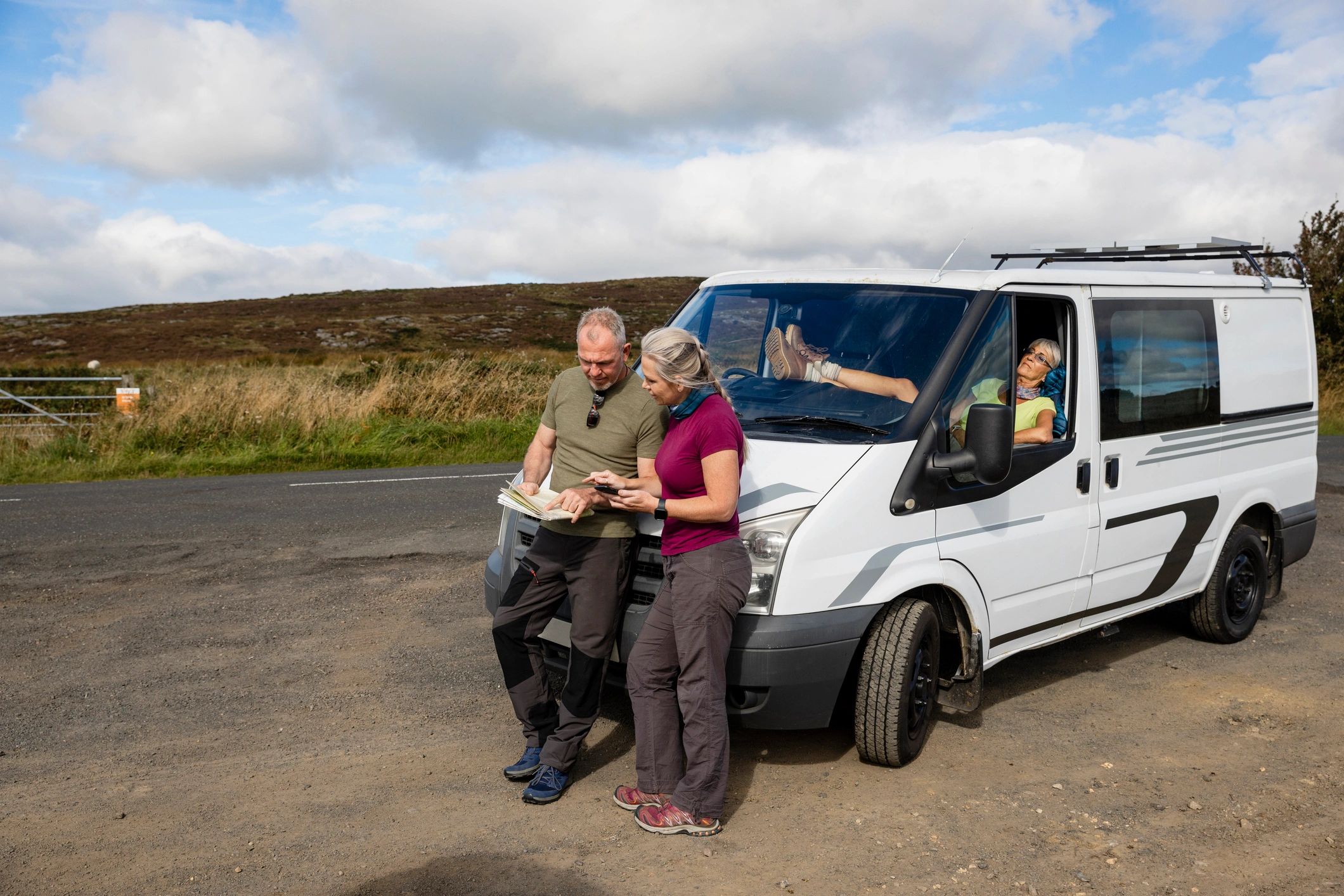 Travelers beside a camper van planning their route